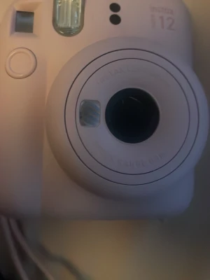 Rosa Fujifilm Instax Mini 12 kamera - Säljer en rosa Fujifilm Instax Mini 12 direktbildskamera. Kameran har rundade former, inbyggd blixt och enkel knapp för att ta bilder. Perfekt för att få ut fysiska foton direkt. Nästan helt oanvänd, priset kan diskuteras 