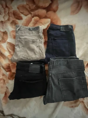 Fyra par jeans i olika färger - Säljer fyra par jeans i olika färger: ett par beige, ett par mörkblå, ett par svarta och ett par grå. Klassisk femficksmodell med raka ben. Perfekta basjeans för garderoben och passar till det mesta. Märken och material varierar mellan paren.