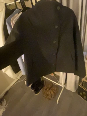 Svart ullkappa med knappar - En svart-mörk grå kort kappa, från lager157 aldrig använd, original pris är runt 450kr säljer den för 200kr vid snabbt köp, storlek XL