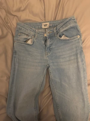 Ljusblå raka jeans från 157 - Säljer ett par ljusblå jeans från 157 med klassisk femficksmodell och raka ben. Jeansen har normal midja, bälteshällor och en snygg tvättad look. Tillverkade i denim med en avslappnad passform, perfekta till en casual stil.