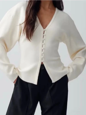 Krämvit topp med knappar  - Stilren krämvit kofta med v-ringning och dekorativa knappar framtill. Koftan har lång ärm och rak passform, perfekt att matcha med både jeans och kjol. Tröjan är i toppskick, skriv för frågor.