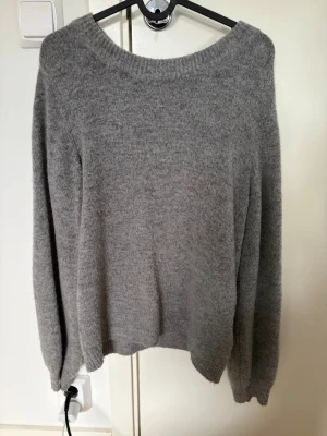 Grå stickad tröja från Object - Mysig grå stickad tröja från Object med rund halsringning och långa ärmar. Tröjan har en enkel och stilren design, perfekt för lager på lager och passar till det mesta. Materialet känns mjukt och behagligt mot huden.