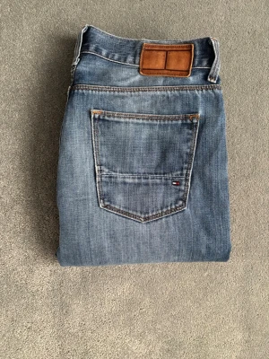 Vintage Tommy Hilfiger jeans - Säljer dessa riktigt feta jeans från Tommy Hilfiger. Jeansen har en snygg ljusblå tvätt, perfekt att ha nu till våren! Storlek W32 L33.  Längd 103cm midja bredd 40cm. Hör av dig vid minsta fundering!😊