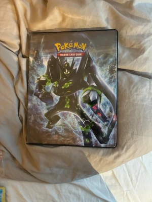 Gamal Pokémon samlarpärm med kort - Säljer en Pokémon samlarpärm med motiv av Zygarde på framsidan. Pärmen innehåller flera Pokémonkort i plastfickor. Perfekt för dig som vill utöka din samling eller börja samla Pokémonkort.       Vissa kan vara falska vet ej!!