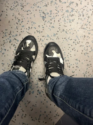Valentino Rockrunner - Tjena! Säljer ett par snygga sneakers från Valentino med svart, grå och vit camo-mönster. Skorna har svarta snören, detaljer i mocka och läder samt nitar på sulan. Perfekta för dig som vill sticka ut med en unik streetstyle. Perfekta inför alla årstider. Storlek 44. Nypris 6000kr Mitt pris 1250.  Hör av dig om eventuella frågor.  Allt orginal medföljes! Dessa skor är relativt använda därmed ett rebbaterat pris 