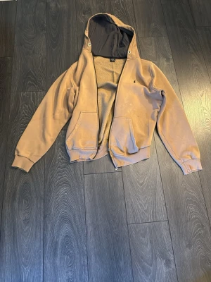Beige hoodie med dragkedja - Snygg beige hoodie från Polo Ralph Lauren med dragkedja framtill och två stora fickor. Mörkgrått innerfoder i huvan och liten broderad logga på bröstet. Tillverkad i mjukt bomullsmaterial, perfekt för en avslappnad stil.
