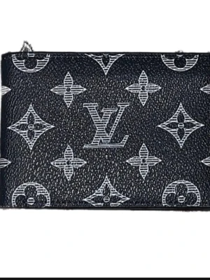 Svart L plånbok - Snygg svart plånbok från L med klassiskt monogrammönster i vitt. Tillverkad i strukturerat läder och har en stilren, rektangulär form. Perfekt för dig som gillar exklusiva accessoarer med ikonisk design.