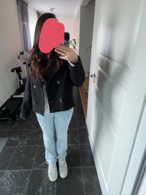 Svart dubbelknäppt rock Vero Moda - Kort svart rock från Vero Moda med dubbelknäppning och bred krage. Klassisk och stilren modell som passar perfekt till jeans eller kjol. Tillverkad i ett mjukt material med slät insida för extra komfort.