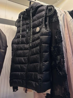 Moncler väst äkta fint skick XS - Säljer en svart Moncler väst i storlek XS. Väldigt fint skick, sparsamt använd.  Perfekt till vår/höst och lätt att matcha. Äkta (logga & detaljer syns på bilder).