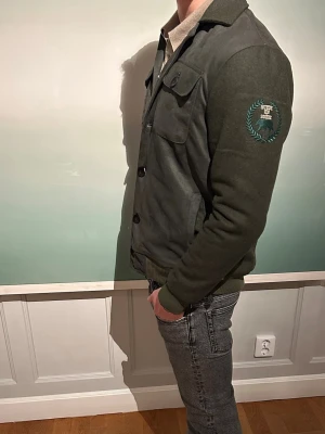 Grön Mockajacka - Grön jacka i faux suede material från märket NorthCouture. Säljes helt ny och priset är fast. Finns i storlekarna M, S och XS. 