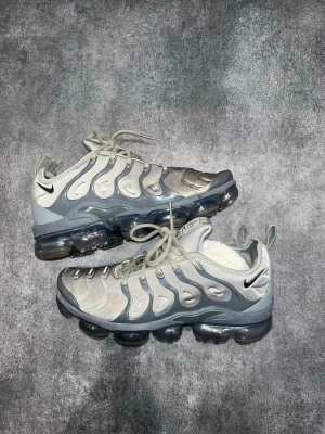 Nike VaporMax Plus - Nike Air VaporMax Plus i grå/silver. Storlek 42,5.  Mycket bra skick överlag. Finns en liten slitning på högerskon vid stortån (sista bilden)