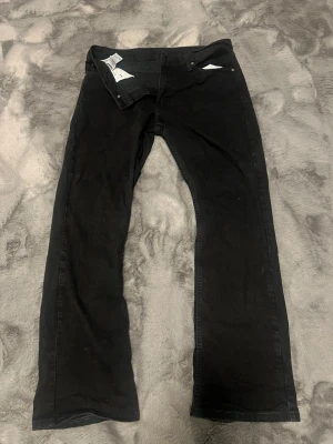 Svarta Levi's 527 jeans bootcut - Svarta jeans från Levi's modell 527 med klassisk bootcut-passform. Snyggt femficksutförande och Levi's patch baktill. Jeansen är gjorda i slitstarkt bomullsmaterial och har en rak siluett med lite vidare ben nedtill.  Svarar ej på bud under 1000 kr då jeansen är i nyskick 