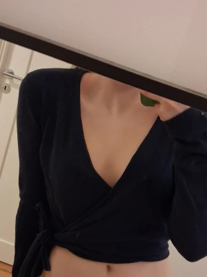  omlott kofta 💕 Brandy mellville - Snygg svart omlottopp med djup v-ringning och knyt i sidan . Toppen är croppad och har långa ärmar. Den är från Brandy Melville.
