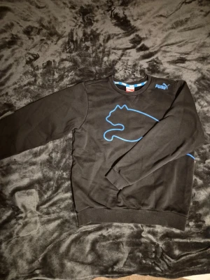 Svart Puma tröja - Svart Puma tröja med blå detalj. Storlek 164