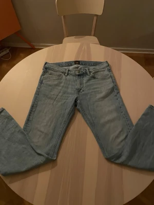Ljusblå raka jeans från Lee - Säljer ett par ljusblå jeans från Lee med klassisk femficksmodell och raka ben. Jeansen har normal midja och Lee-logga på bakfickan. Perfekta för en avslappnad och stilren look.