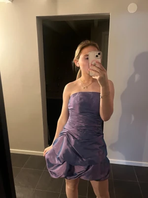 Lila axelbandslös kortklänning - Säljer en lila axelbandslös kortklänning som passar perfekt till tema fest💕💕