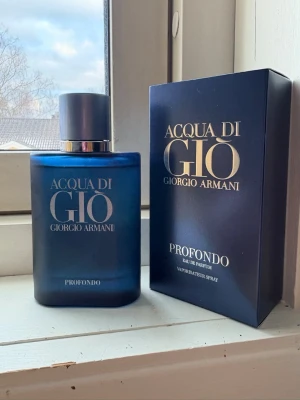 Acqua di Giò Profondo parfym - Acqua di Giò Profondo från Giorgio Armani är en elegant parfym i en matt mörkblå glasflaska med silverfärgat lock och präglad logotyp. Doften är Eau de Parfum och flaskan har en stilren, modern design med tillhörande mörkblå kartong.