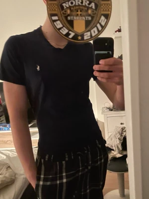 Marinblå t-shirt - Snygg mörkblå t-shirt från Ralph Lauren med klassisk v-ringning och den ikoniska logon broderad på bröstet. T-shirten har en slim passform och är tillverkad i mjuk bomull som känns skön mot huden. Andvänd fåtal gånger, säljer för den börjar bli för liten. Kom med bud och frågor, passar runt 175-180