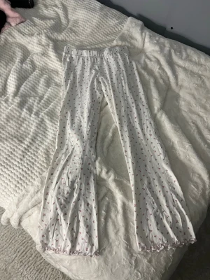 pyjamasbyxor med blomdetaljer - Vita tunna pyjamasbyxor med blomdetaljer. Säljer pga att de inte används. Superskönt material och sitter snyggt! 