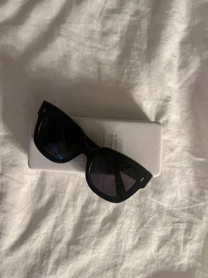 Chimi butterfly - Snygga svarta solglasögon från Chimi med bred båge och fyrkantig form. Glasen är mörka och ramen är tillverkad i blank plast. Perfekta för dig som vill ha en stilren och trendig look. Medföljer vit hård förvaringsbox med CHIMI-logga (fodralet är lite sönder på insidan) Hör av er vid mer frågor💞