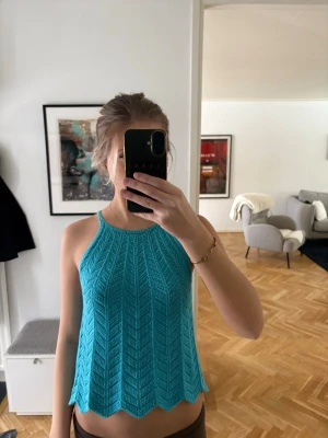 Turkos stickad linnetopp - Snygg turkos stickad linnetopp med smala axelband och vågig nederkant. Toppen har ett coolt mönster i stickningen. Passformen är loose och toppen är ärmlös.