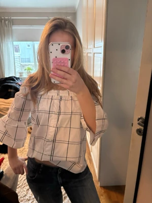 Rutig rekvartsärmad skjortblus! - Söt vit blus med svarta rutor och off-shoulder-modell, men går att ha vanligt också! Vida trekvartsärmar och knappar framtill. Skriv om du har några funderingar!😊 