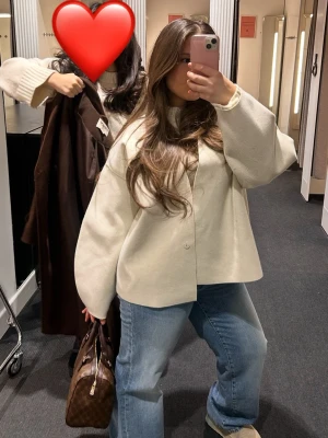 Beige jacket i ullmix - Stilren beige jacka med knappar framtill och avslappnad passform. Jackan har lång ärm och är tillverkad i en mjuk ullblandning, perfekt för lager-på-lager-stil. Enkel design som passar till jeans och sneakers.