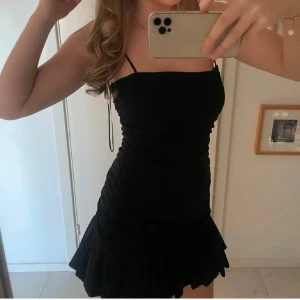Svart kort festklänning från Zara  - Perfekt nyårsklänning!!! Säljer denna svarta klänning med volang nertill  från Zara som aldrig använts och som ej säljs längre,  passar perfekt till till fest och utgångar, jättebra och ordentligt material. Pris kan diskuteras, hör av dig vid frågor ❤️