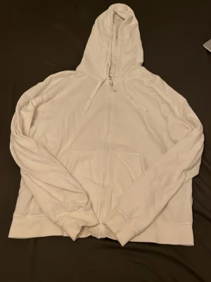Vit zip hoodie från Chimi - Säljer en clean vit hoodie från Chimi med dragkedja framtill, huva med dragsko och känguruficka. Tillverkad i mjukt bomullsmaterial som känns skönt mot huden. Perfekt för en chill och stilren look.