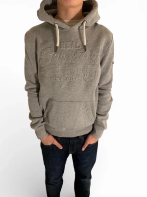 Grå hoodie från Superdry - As fet grå hoodie med vita vita snören i storlek S, skicket är helt ny.  pris ej hugget i sten vid snabb affär. Hör av dig vid minsta fundering👍