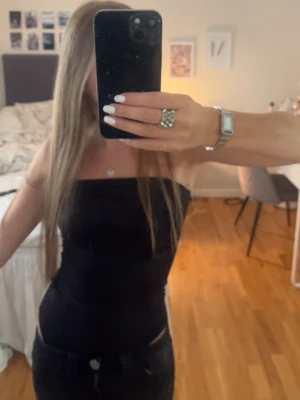 Svart bandeau tubbody - Snygg svart bandeau tubbody som sitter tight och är perfekt för en trendig look. Toppen är axelbandslös och har en enkel, stilren design som passar till många olika outfits.