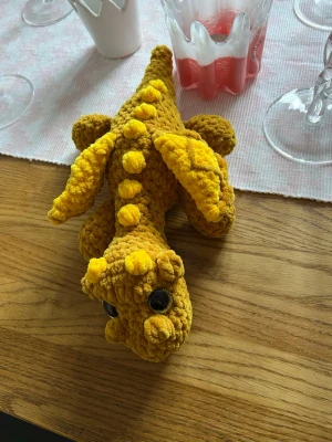 Gulbrun drake med gula detaljer - Även denna urgulliga drake längtar efter sitt för alltid hem💛🤎💛🫶🏼✨ Det är en gulbrun drake med gula detaljer, virkat med mjukt garn från Hobbii som heter Baby Snuggle🫶🏼 Den har hårda guldiga ögon som inte går att ta av, sitter som bergen✨💛 Den är cirka 30 cm lång💛