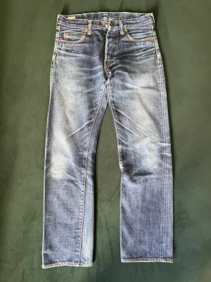SKIT FETA MOMONTARO  - Säljer ett par blå raka jeans snyggt slitna detaljer och klassisk femficksmodell. Jeansen har kontrastsömmar, patch bak i midjan och tre vita ränder på ena bakfickan. Tillverkade i bomull för en skön känsla.