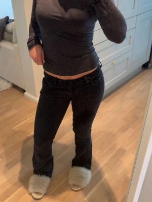 Svarta bootcut jeans med låg midja - Säljer ett par svarta bootcut jeans med låg midja och klassisk femficksdesign. Jeansen har utsvängda ben och är tillverkade i stretchigt denimtyg som sitter snyggt. Perfekta för dig som gillar en trendig och avslappnad stil.