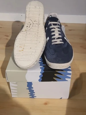 Blå och vita sneakers från Premiata - Snygga sneakers från Premiata i mörkblå mocka med vita detaljer och vita skosnören. Pris 1500 inte hugget i sten.