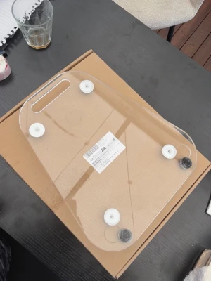 Transparent bricka i akryl med handtag till thermomix  - Säljer en stilren transparent bricka i akrylplast med rundade hörn och ett praktiskt handtag. Brickan har fyra vita fötter undertill för stabilitet och är perfekt för servering eller dekoration. Enkel och modern design som passar in överallt.