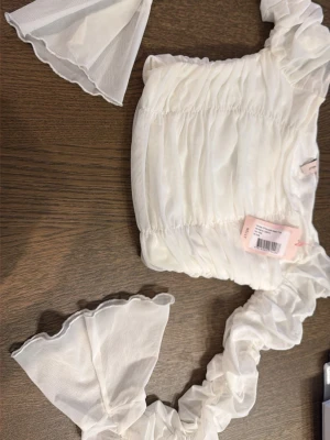 Vit volang topp från Nelly - Supersöt vit topp från Nelly med volangdetaljer och puffiga ärmar. Toppen har en rynkad design och är tillverkad i ett tunt, lätt material som ger en romantisk känsla. Perfekt för dig som vill sticka ut med en feminin och trendig look. Ny pris 249kr.