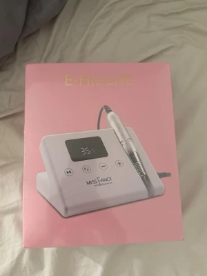 E-File LITE nagelfil från Miss Fancy - Helt ny och oöppnad elektrisk nagelfil E-File LITE från Miss Fancy Professional. Svart maskin med digital display och silverfärgad handdel. Perfekt för att fila och forma naglar, både naturliga och konstgjorda. Levereras i rosa förpackning med tekniska specifikationer på sidan. Nypris: 799kr