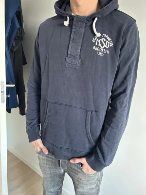 Scotch & Soda - Schysst mörkblå Scotch and soda hoodie. Hoodien är som en half zip fast med snygga dolda knappar istället för en skön look på den. Hör av er vid minsta lilla fråga😁