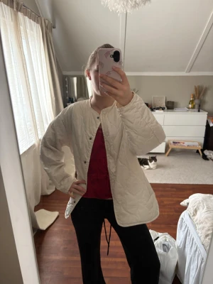 Beige quiltad teddyjacka - Säljer en beige quiltad teddyjacka med rund halsringning och tryckknappar framtill. Jackan har en avslappnad passform och är tillverkad i ett mjukt, vadderat material som ger en mysig känsla. Perfekt för lager på lager och enkel att styla till olika outfits. Storlek Xs men tycker den är med som en M
