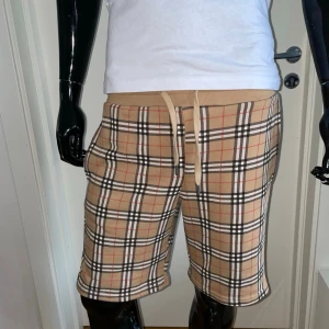 Burberry Shorts, Beige, Storlek S - Helt ny, högkvalitativ replika  Skyldockan på bilden är 175 cm lång och bär storlek S.  Pris: 899kr  Leverans: Skickas inom 24 timmar  Observera: Begränsat antal i lager – först till kvarn gäller  