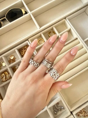 Tre chunky silverringar - Säljer ett set med tre coola silverfärgade ringar. En har flera tunna band, en har ett organiskt, hamrat mönster och den tredje har ett geometriskt, blockigt mönster. Perfekt för dig som gillar statement-accessoarer och att mixa olika stilar.
