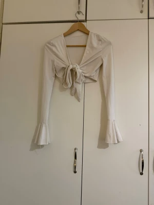 Vit omlottopp med knyt och volangärm - Trendig vit omlottopp med knyt framtill. 