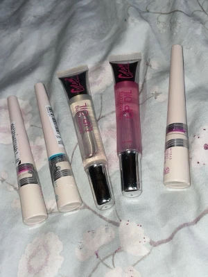 Läppglans och eyeliner från Viva la Diva - Säljer två läppglans från Viva la Diva, ett transparent och ett rosa, båda i tub med silverlock. Medföljer även tre flytande eyeliners i vita hylsor med färgmarkeringar. Perfekt för dig som vill ha glansiga läppar och markerad eyeliner.