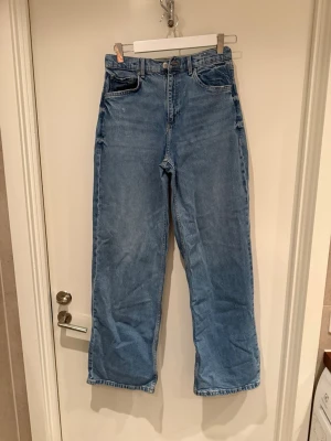 Blåa raka jeans  ( Baggy jeans) - Säljer ett par klassiska blå jeans med rak passform.  Jeansen har fem fickor och stängs med dragkedja och knapp. Tillverkade i denim med en avslappnad look, perfekta till vardagsstilen.