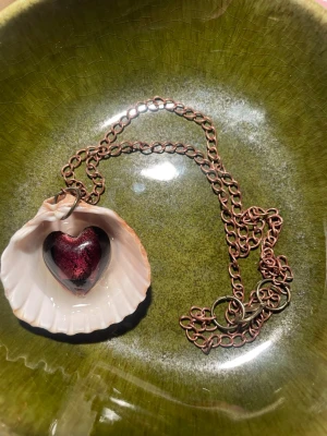 Handgjort halsband  med snäcka och hjärthänge - Unikt halsband med en kedja i kopparfärg och ett hänge av en vit snäcka. Inuti snäckan sitter ett glansigt hjärta i lila. Perfekt för dig som gillar naturinspirerade accessoarer och vill sticka ut. Handgjort av mig.
