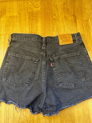 Svarta jeansshorts från Levi's - Säljer mina Levi's shorts som jag tyvärr inte längre kan ha, supersnygga och passar till allt!  Storleken motsvarar 34/36 i passform