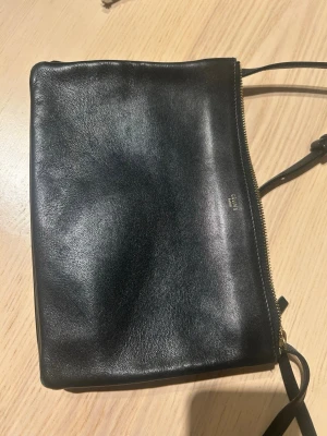 Céline trio bag - small/svart - Klassisk trio svart axelväska från Celine i slätt läder med justerbar axelrem och guldfärgad dragkedja. Väskan har en minimalistisk design med diskret logga framtill och passar perfekt för dig som gillar klassiska accessoarer. Köpt i Paris, kvitto finns ej kvar men äkthet är verifierad. 