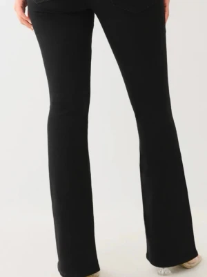 Svarta bootcut jeans - Snygga svarta bootcut jeans med klassisk femficksmodell och hög midja. Jeansen har en figurnära passform upptill och utsvängda ben. Perfekta att styla med sneakers eller klackar för en trendig look.