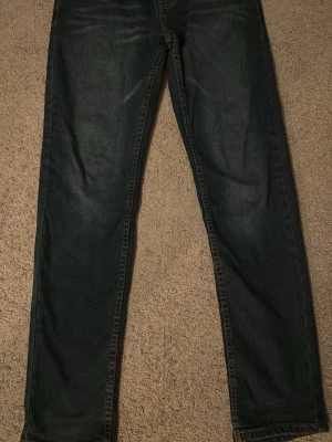 Levi's 502 Regular Taper jeans mörkblå - Säljer ett par mörkblå Levi's 502 Regular Taper jeans med klassisk femficksdesign och knappgylf. Jeansen har en avsmalnande passform och är tillverkade i slitstark denim. Perfekta för dig som gillar en tidlös och avslappnad stil.